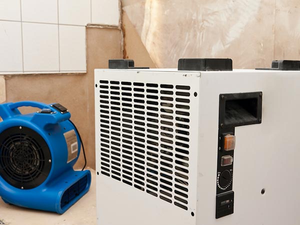 Flood-Damage-Restoration-Pontiac-MI-Michigan-2 | Incore Restoration Group Blue portable air blower sits beside a large white industrial heater with a vented front panel in a workshop.